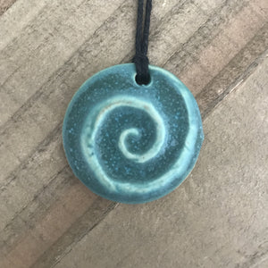 Round pendant necklace with koru spiral. Made of clay, turquoise blue color.